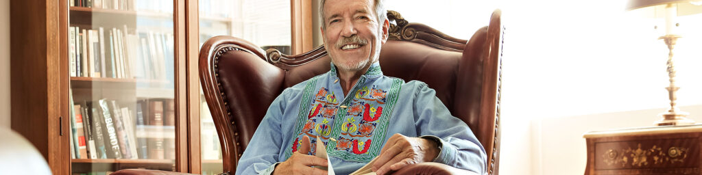 Resident reading in a leather chair with bookshelves in a cozy lounge.
